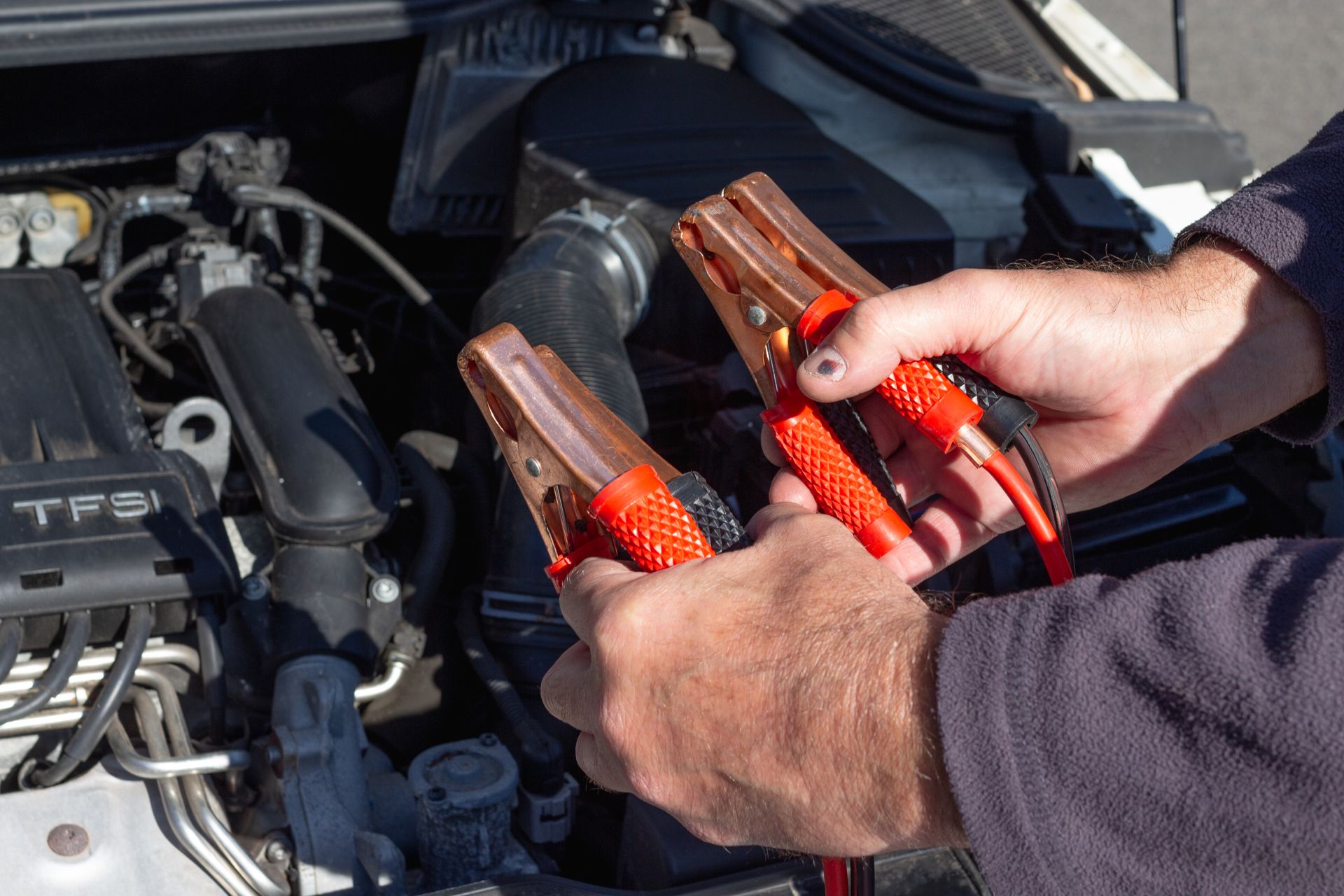 Jumper cable clamps beside a car battery